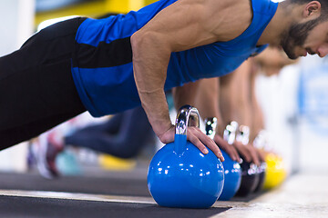 Image showing young athletes doing pushups with kettlebells