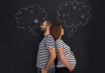 Image showing pregnant couple posing against black chalk drawing board