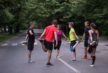 Image showing runners team warming up and stretching before morning training