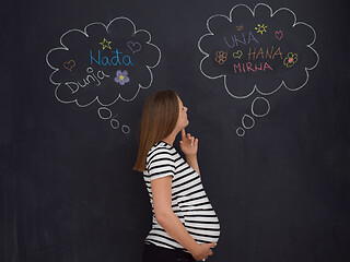 Image showing pregnant woman thinking in front of black chalkboard