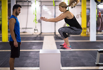 Image showing woman working out with personal trainer jumping on fit box