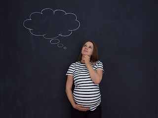 Image showing pregnant woman thinking in front of black chalkboard