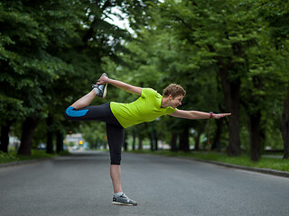 Image showing female runner warming up and stretching before morning training