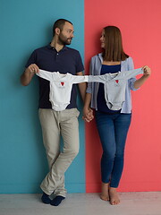 Image showing young couple holding baby bodysuits