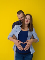 Image showing pregnant couple  isolated over yellow background