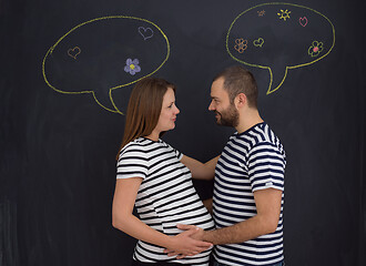 Image showing pregnant couple posing against black chalk drawing board