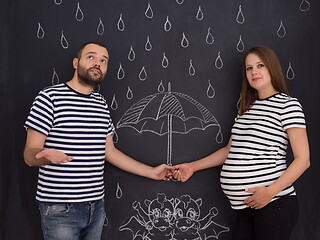 Image showing pregnant couple drawing their imaginations on chalk board