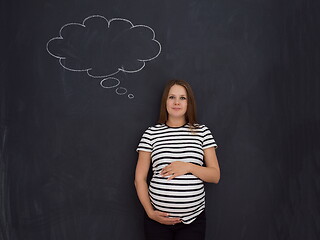 Image showing pregnant woman thinking in front of black chalkboard