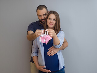 Image showing pregnant couple holding newborn baby shoes