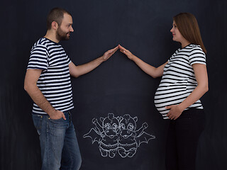 Image showing pregnant couple drawing their imaginations on chalk board