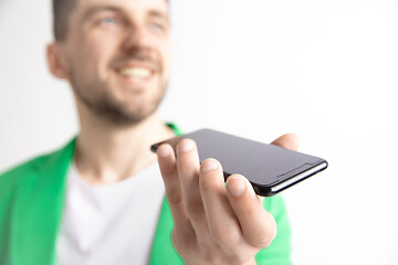 Image showing Indoor portrait of attractive young man holding smartphone