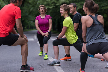 Image showing runners team warming up and stretching before morning training