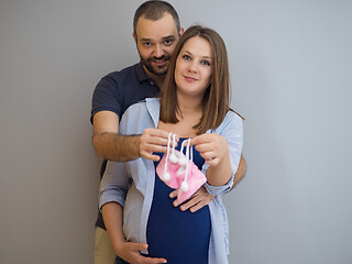 Image showing pregnant couple holding newborn baby shoes