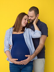 Image showing pregnant couple  isolated over yellow background