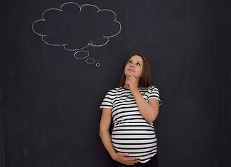 Image showing pregnant woman thinking in front of black chalkboard