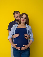 Image showing pregnant couple  isolated over yellow background