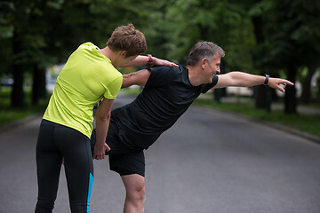 Image showing runners team warming up and stretching before morning training