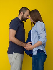 Image showing pregnant couple  isolated over yellow background