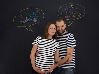 Image showing pregnant couple posing against black chalk drawing board