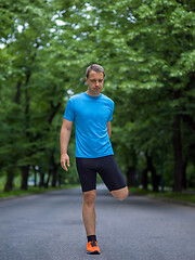 Image showing male runner warming up and stretching before morning training