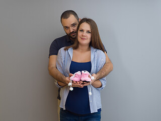 Image showing pregnant couple holding newborn baby shoes