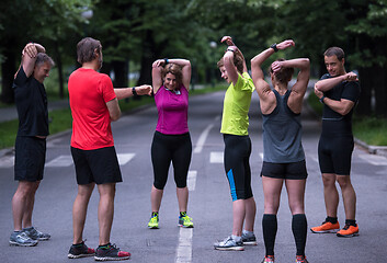 Image showing runners team warming up and stretching before morning training