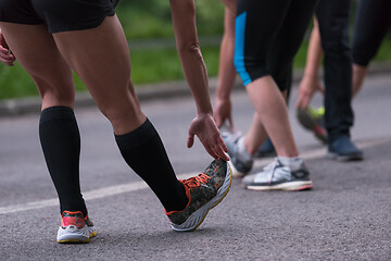 Image showing runners team warming up and stretching before morning training