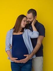 Image showing pregnant couple  isolated over yellow background