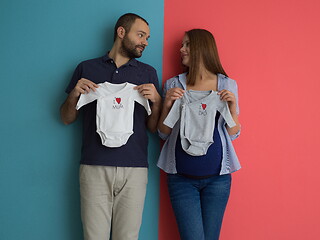 Image showing young couple holding baby bodysuits