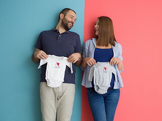 Image showing young couple holding baby bodysuits