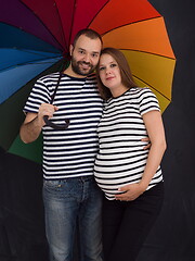 Image showing pregnant couple posing with colorful umbrella