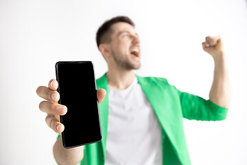 Image showing Young handsome man showing smartphone screen and signing OK isolated on gray background