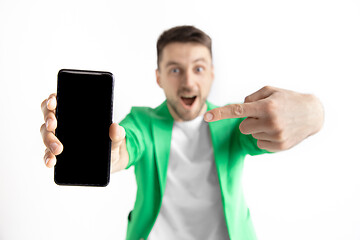 Image showing Young handsome man showing smartphone screen and signing OK isolated on gray background