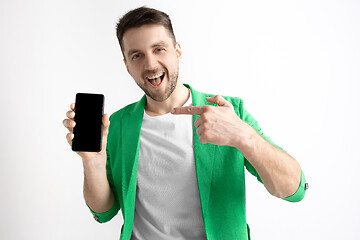 Image showing Young handsome man showing smartphone screen and signing OK isolated on gray background