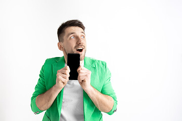 Image showing Young handsome man showing smartphone screen and signing OK isolated on gray background