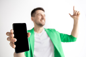 Image showing Young handsome man showing smartphone screen and signing OK isolated on gray background