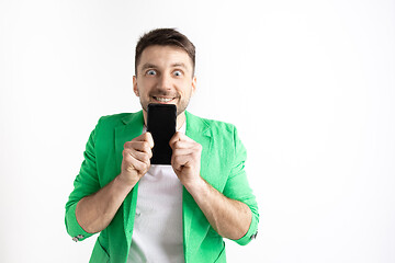 Image showing Young handsome man showing smartphone screen and signing OK isolated on gray background