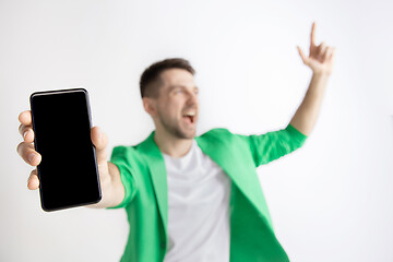 Image showing Young handsome man showing smartphone screen and signing OK isolated on gray background