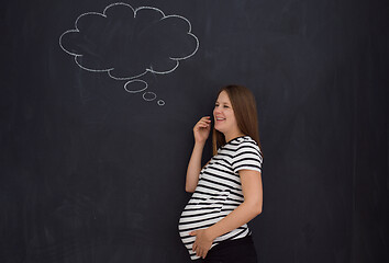 Image showing pregnant woman thinking in front of black chalkboard