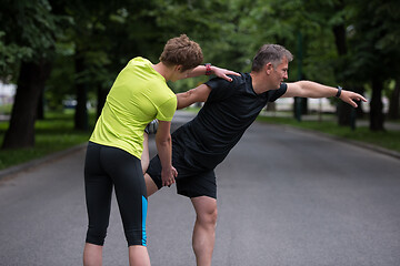 Image showing runners team warming up and stretching before morning training