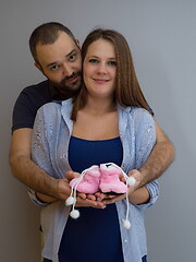 Image showing pregnant couple holding newborn baby shoes