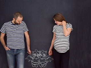 Image showing pregnant couple drawing their imaginations on chalk board