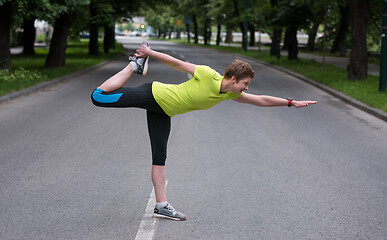 Image showing female runner warming up and stretching before morning training