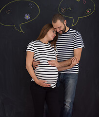 Image showing pregnant couple posing against black chalk drawing board