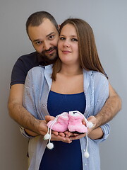 Image showing pregnant couple holding newborn baby shoes