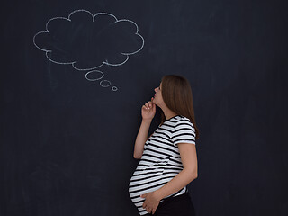 Image showing pregnant woman thinking in front of black chalkboard