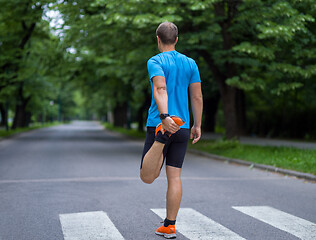 Image showing male runner warming up and stretching before morning training