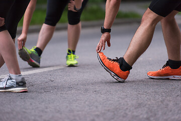 Image showing runners team warming up and stretching before morning training