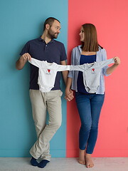 Image showing young couple holding baby bodysuits