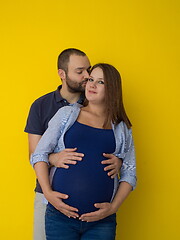 Image showing pregnant couple  isolated over yellow background